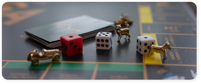 Zbliżenie na metalowe figurki kota, psa i samochodu obok kości do gry na planszy Monopoly